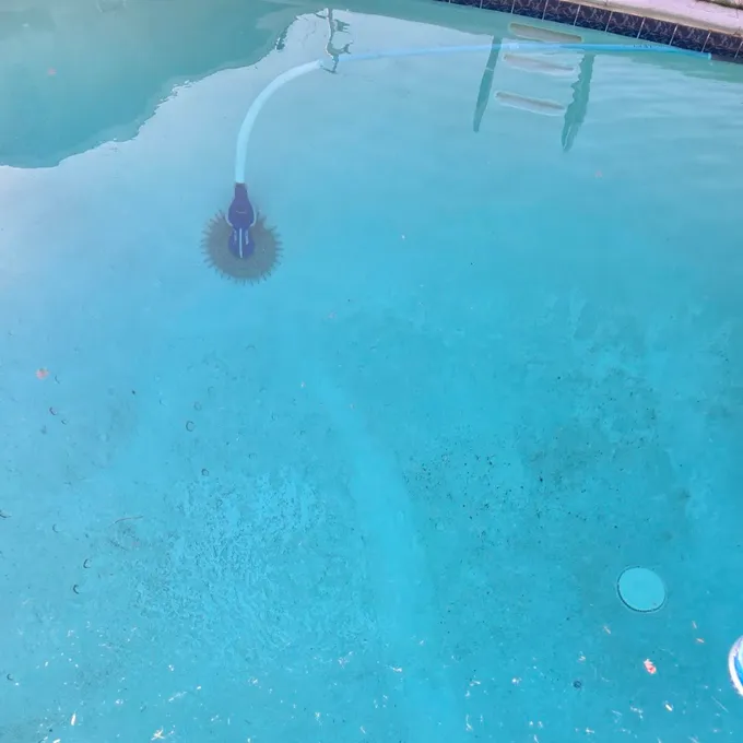 Customer photo attached to the review: blue pool water with a cleaner running